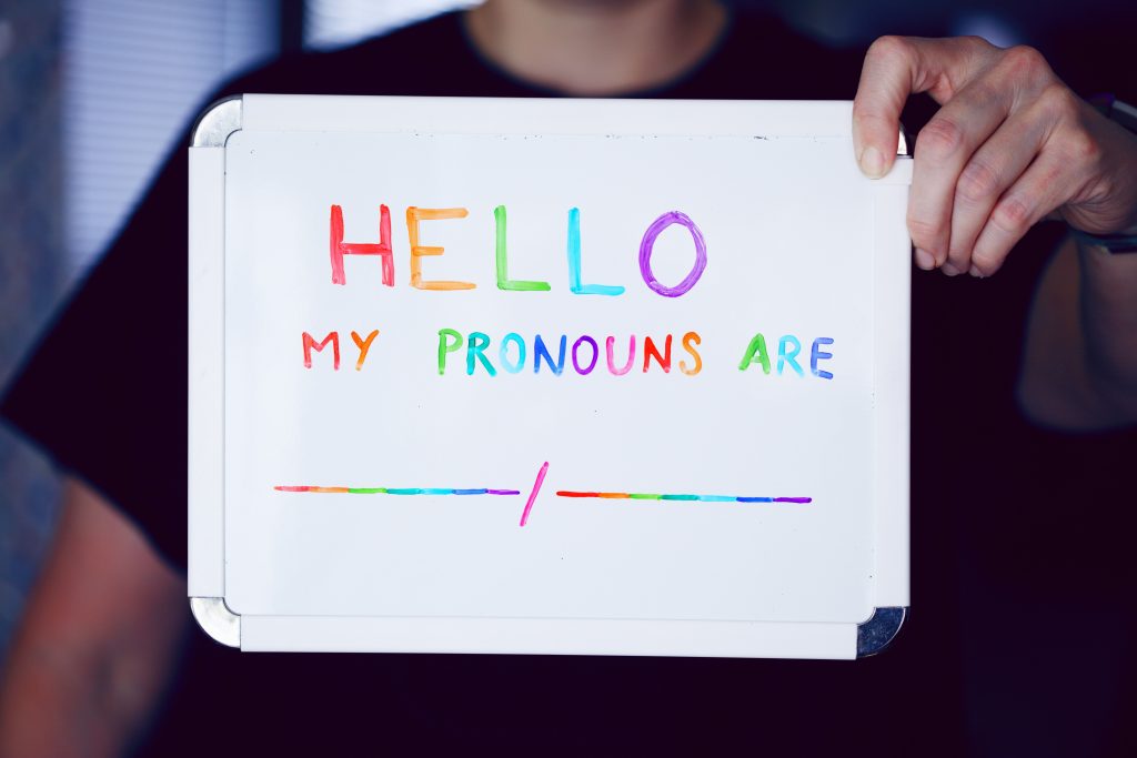 A whiteboard with the statement "Hello, my pronouns are..."