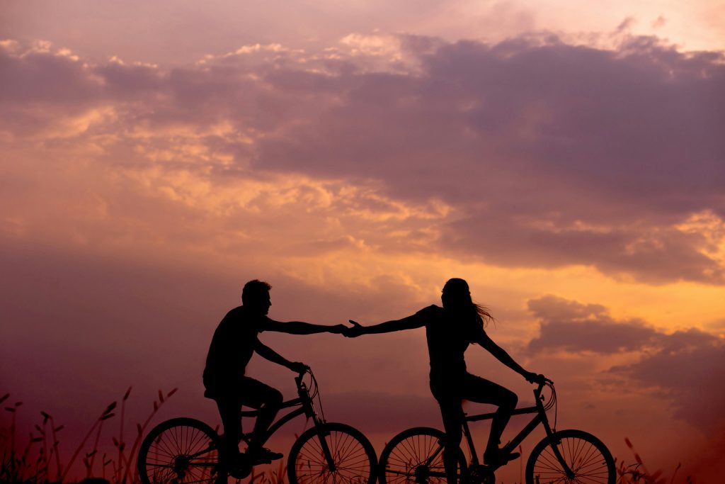 man and woman riding bicycles, in silhouette.