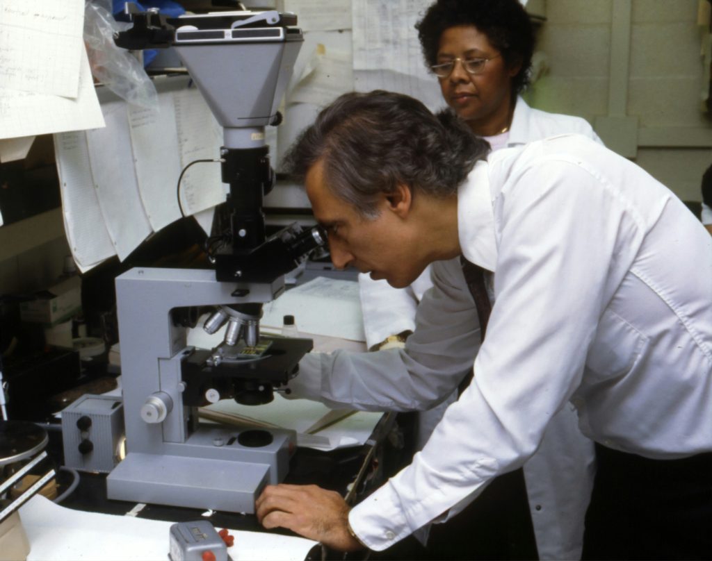 Two people stand over a piece of lab equipment.