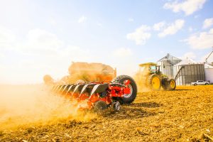 a tractor pulls a tool through a dusty paddock.
